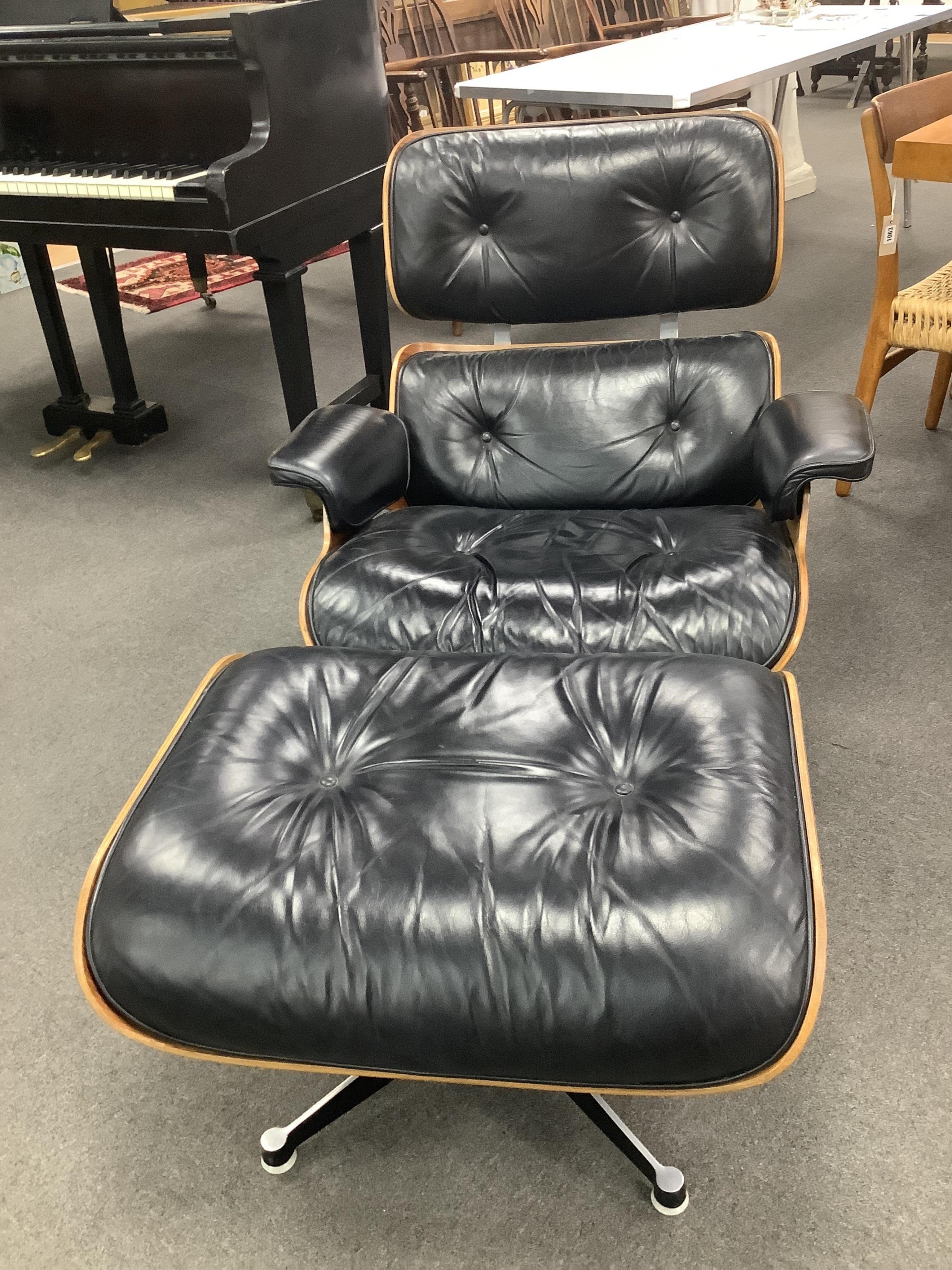 Charles and Ray Eames, a model 670 black leather and Indian rosewood lounge chair, width 85cm, depth 80cm, height 80cm, and a 671 ottoman, manufactured by Hille, London Ltd. Condition - fair to good